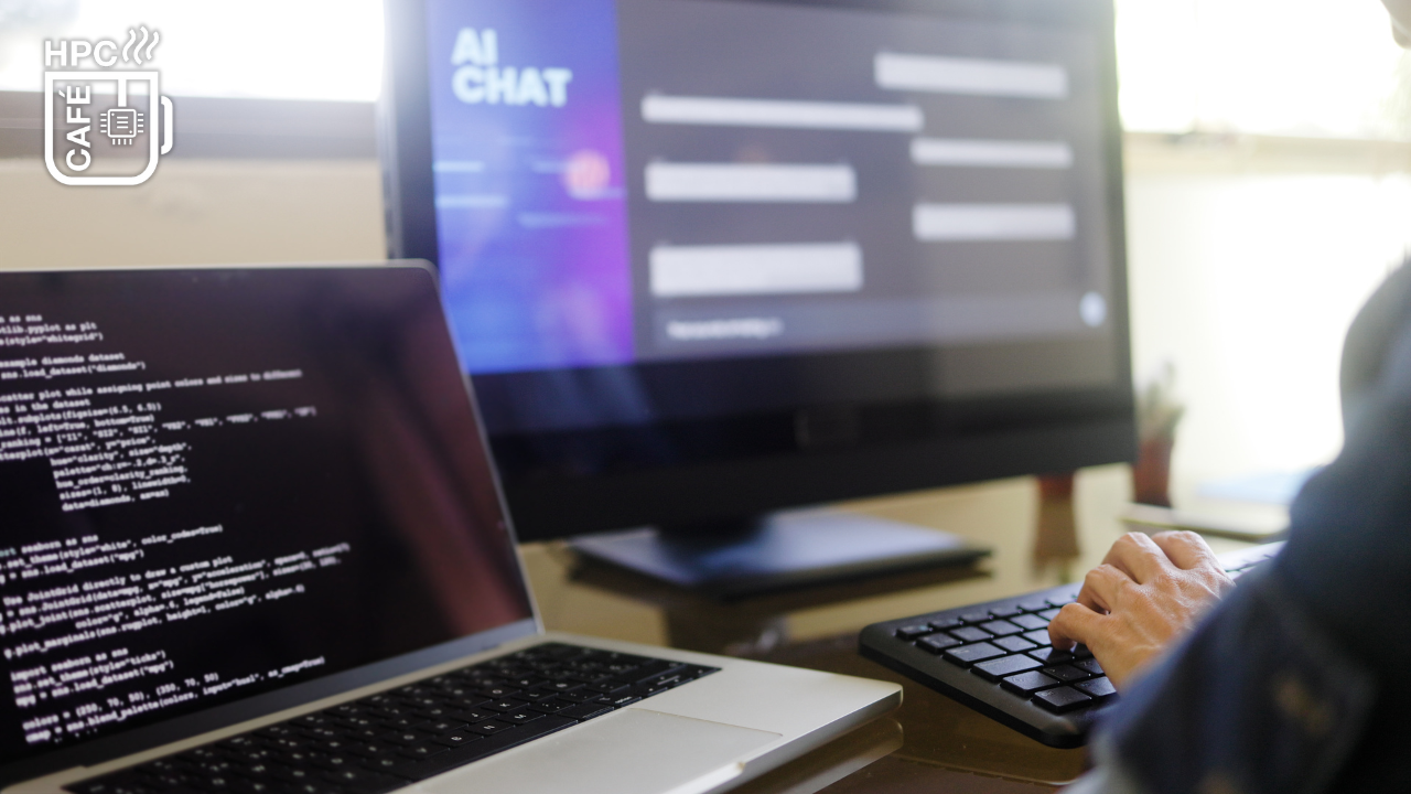 The picture shows a desk and the hands of a person working on two different computers. One is a desktop PC showing an AI chat program, the other is a laptop on displaying code.